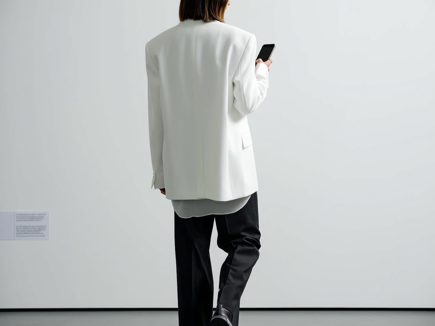 Personne en blazer blanc qui marche en consultant son smartphone